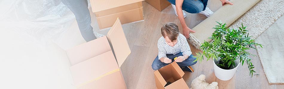 Boy sat on floor playing with toys surrounded by packing boxes