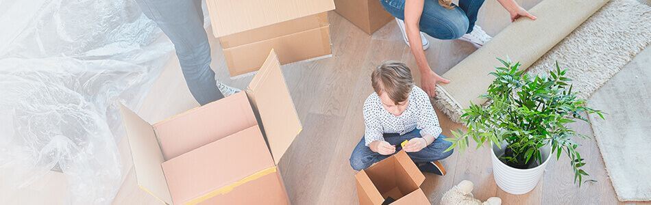 Boy sat on floor playing with toys surrounded by packing boxes small