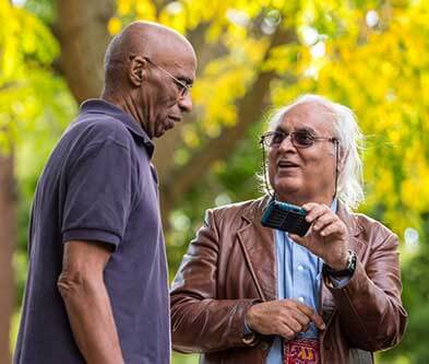 Man with camera talking to other man