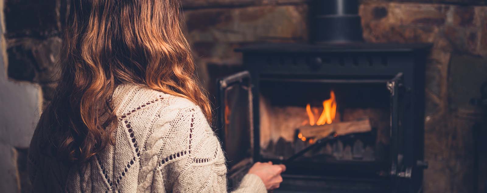 Lady placing wood in fire