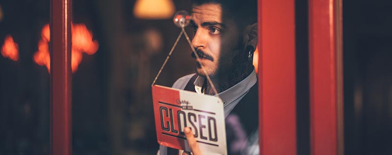 Man flipping closed sign on door