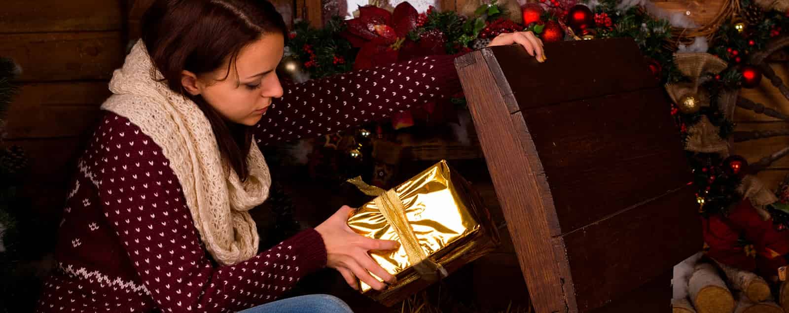 Lady opening wooden chest and holding wrapped gift