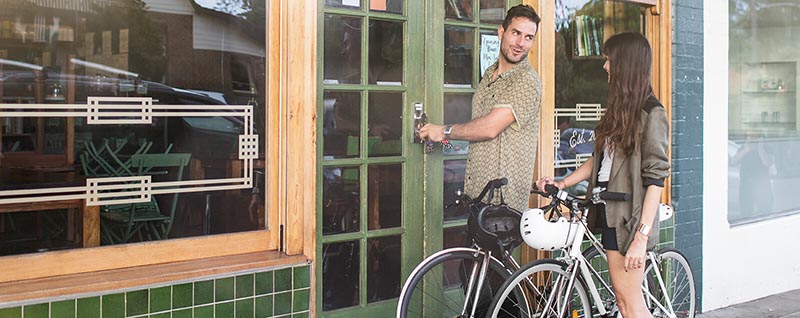 Couple on bikes entering café 
