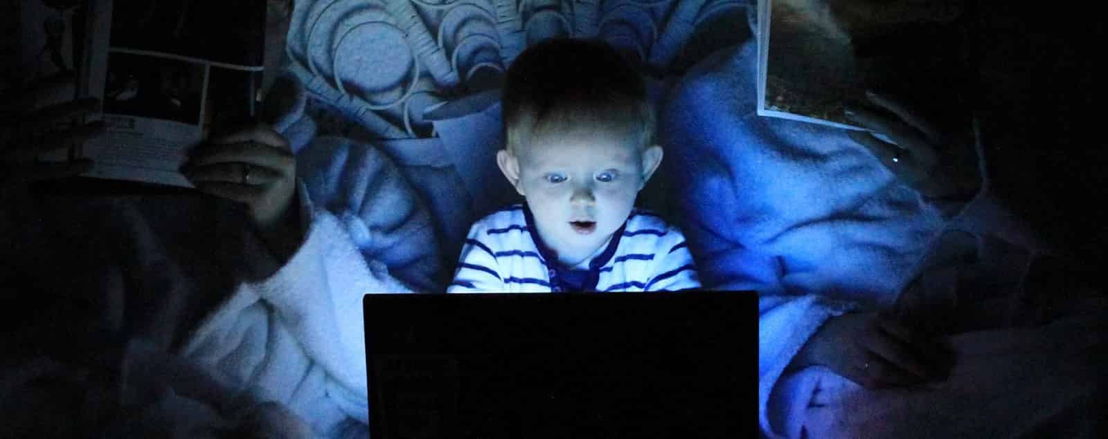 Child using laptop in dark