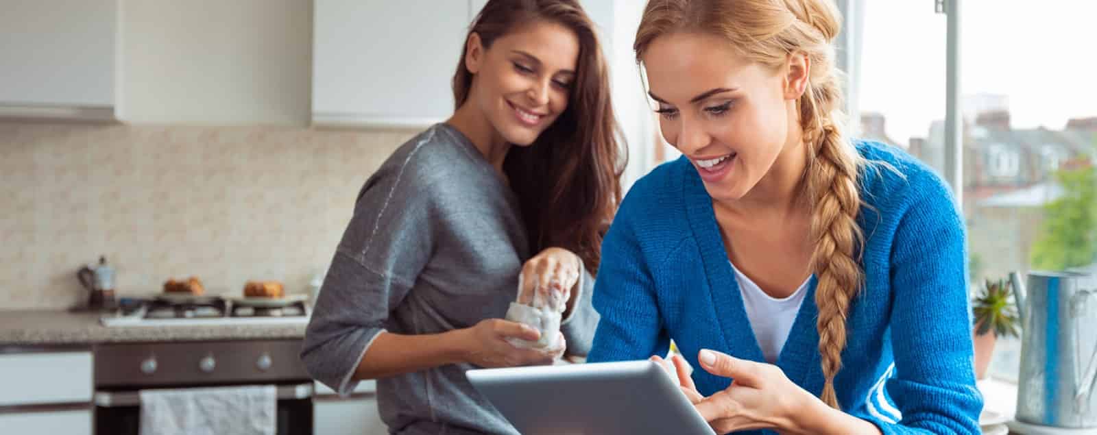 Two ladies in kitchen using tablet