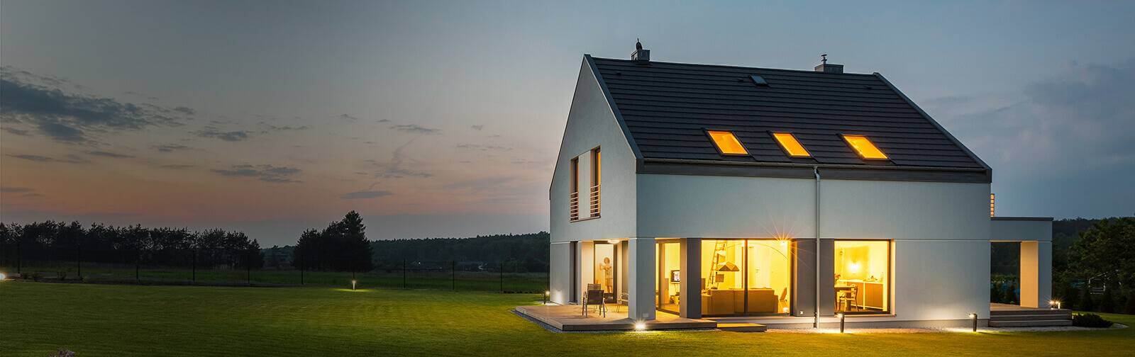 Modern home lit up by interior lights in fading light outside