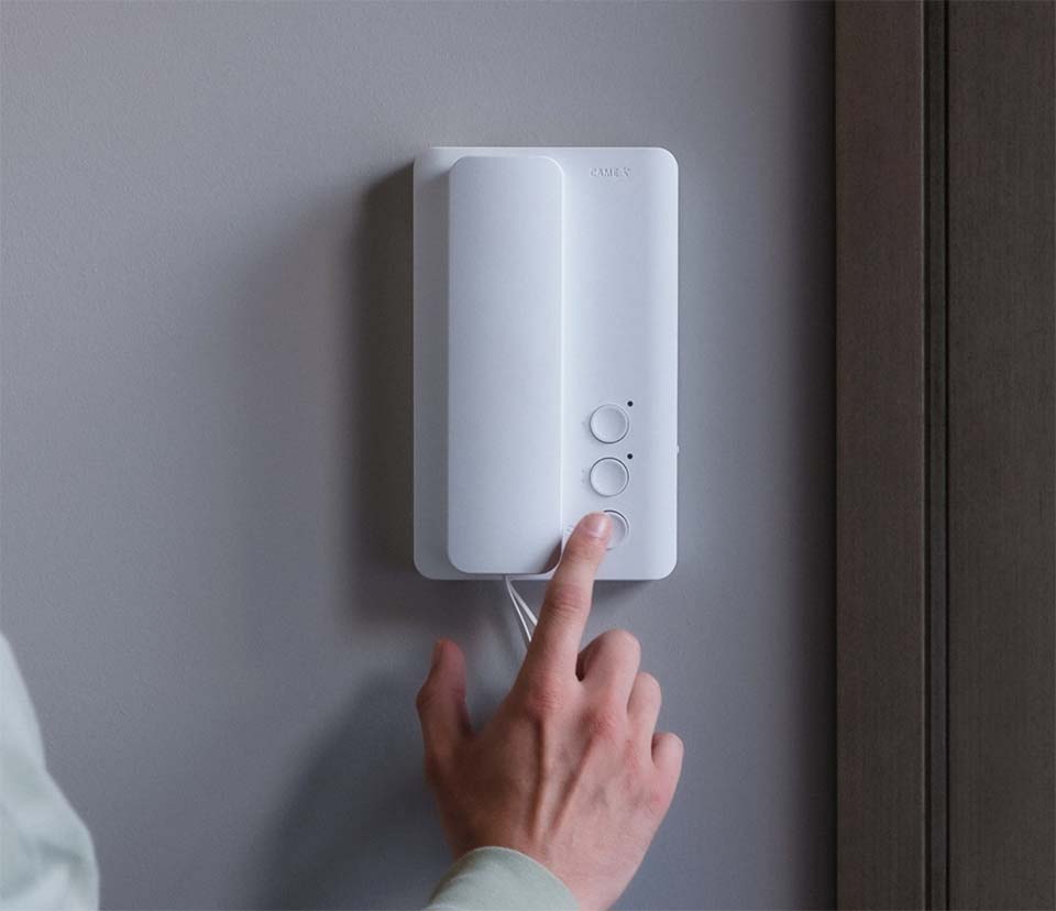 Hand pressing button of wall-mounted home phone