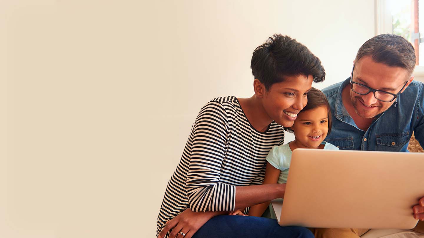 Family of three looking at laptop and smilling