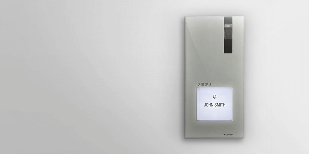 Alarm interface panel with camera and display reading John Smith