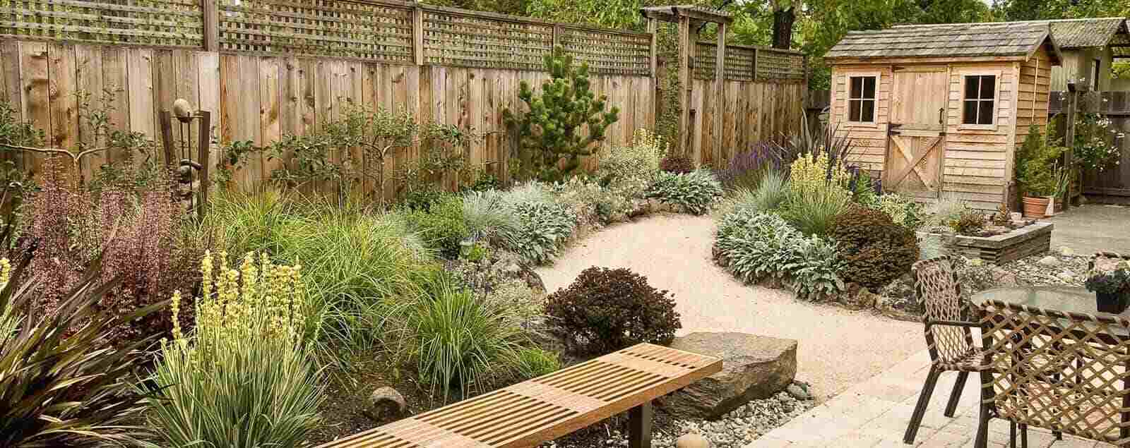 Back garden during the day with shed, fence, bench and table