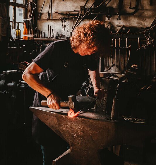 Lady working metal on an anvil