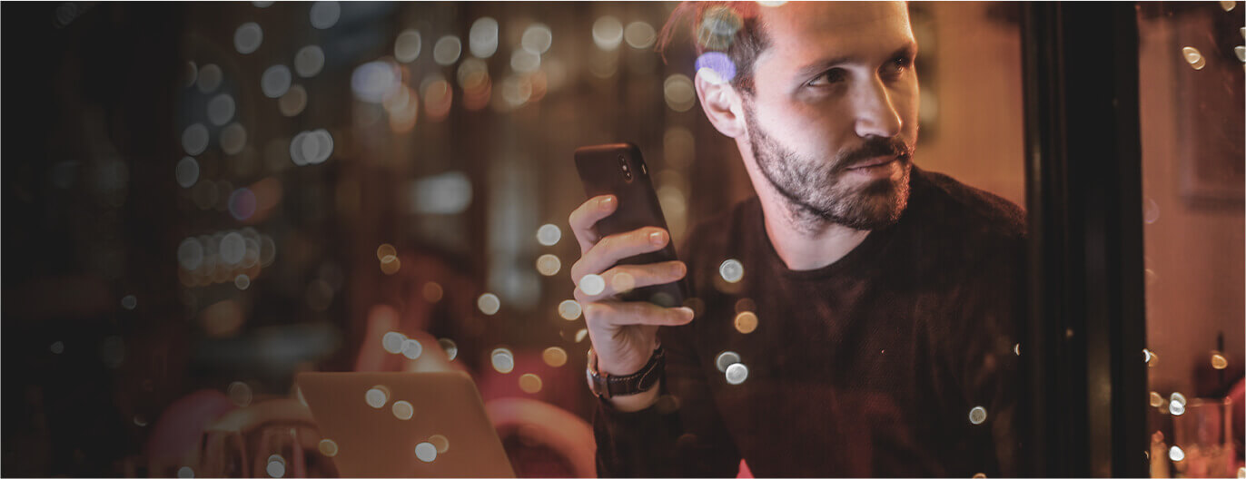 Man next to rainy window with smartphone in hand