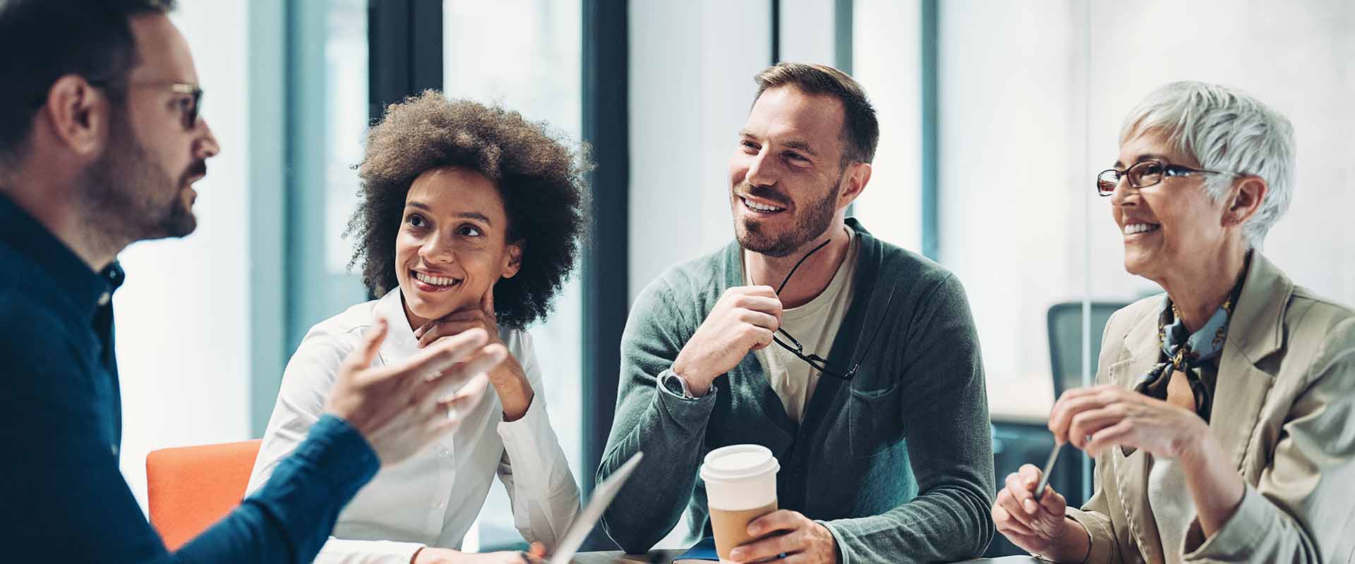 Four people in a meeting smiling