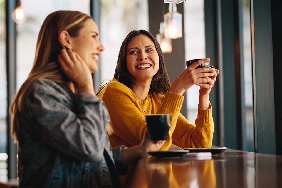 Two ladies talking and smiling over coffee