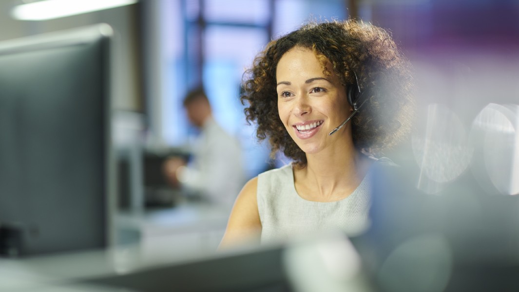 Lady in call centre smiling and wearing a headset