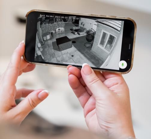 Someone holding a phone which is showing the view from an ADT Outdoor camera