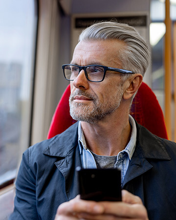 Man on train holding smartphone and looking out of window