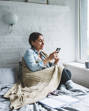Lady sat in bed using smartphone