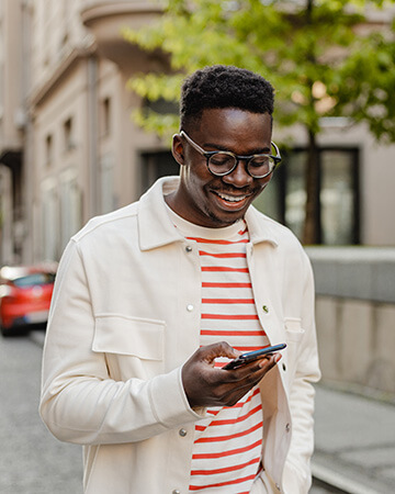 Man walking down street looking down at phone