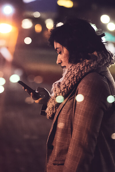 Lady in coat and scarf looking down at phone