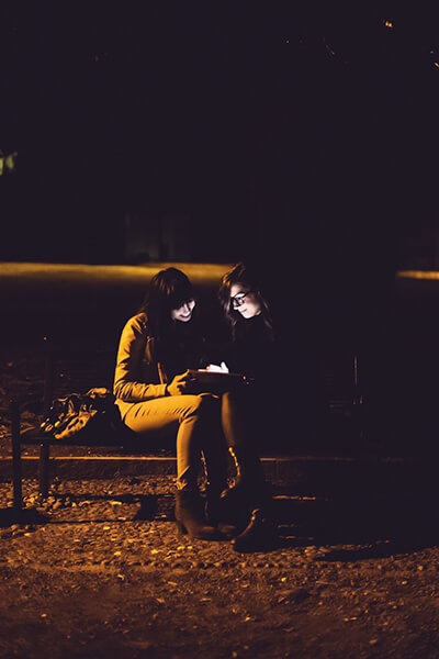 Two ladies using tablet in the dark