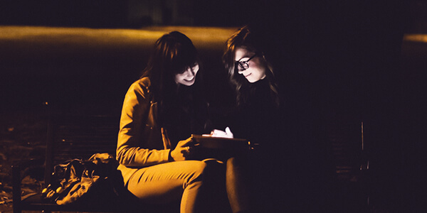 Two ladies using tablet in the dark