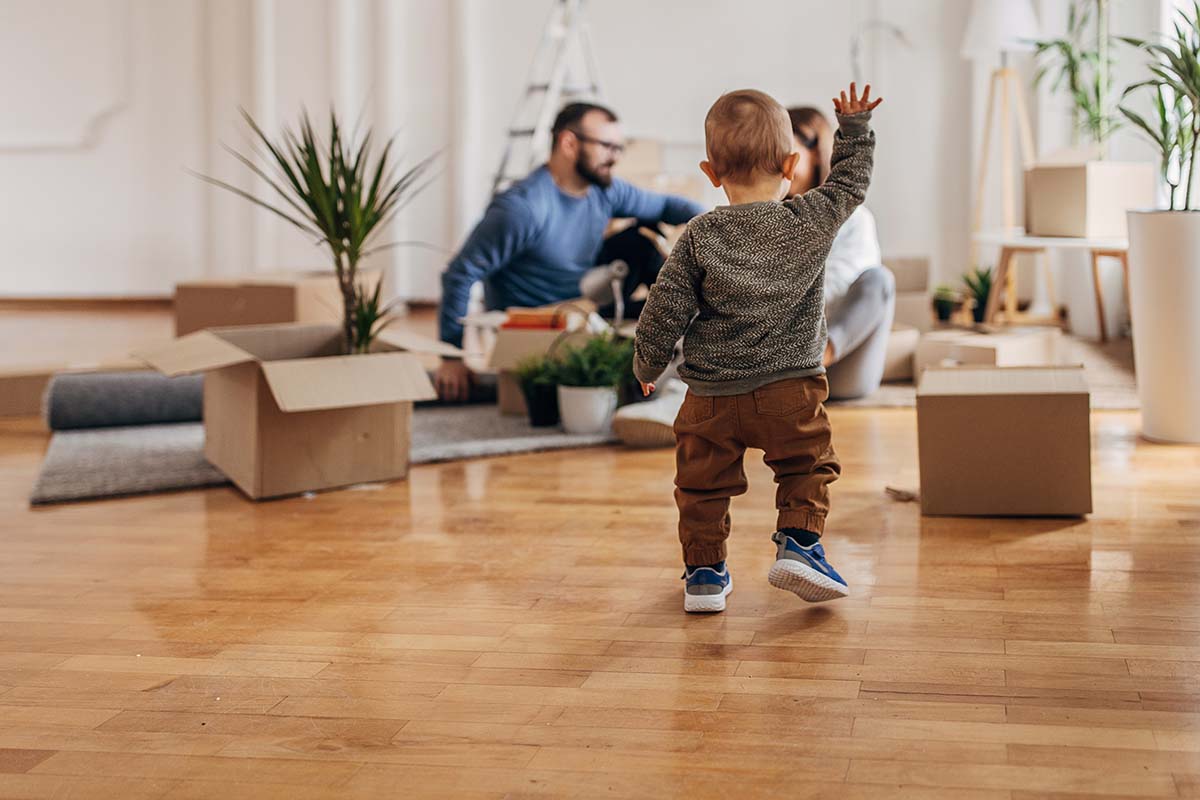 Couple unpacking while child walks towards them