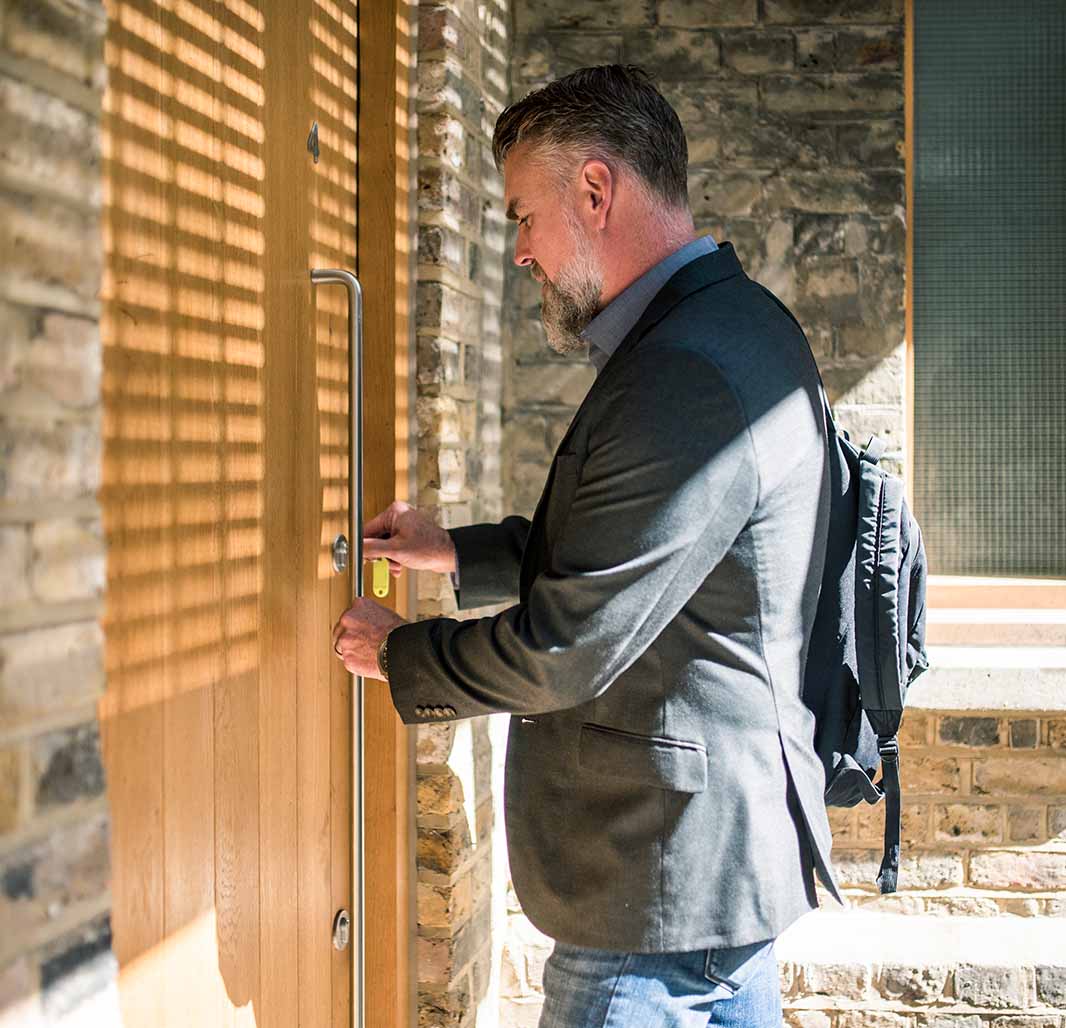 Man putting key into the lock of his house's front door