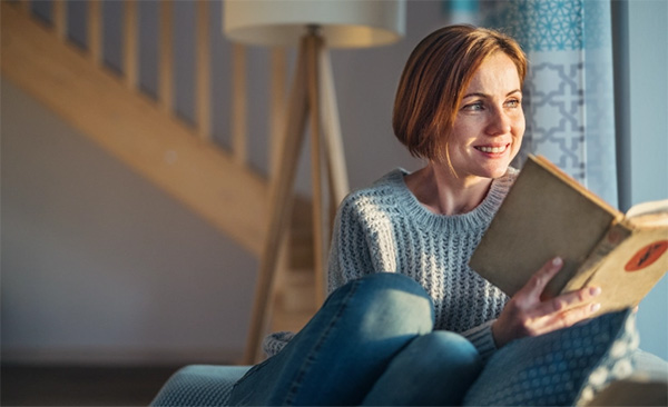 Lady reading book and looking out of window