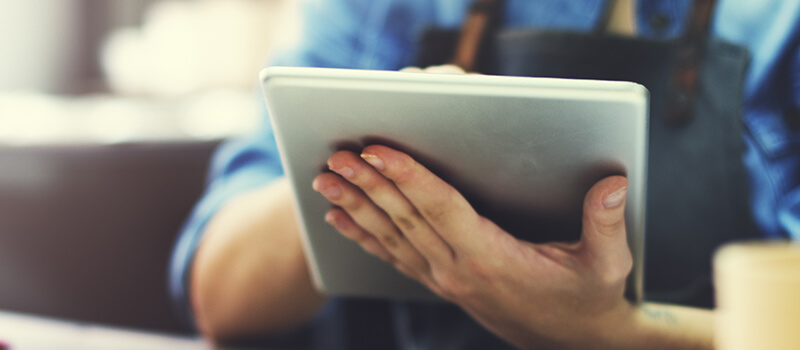 Torso shot of person wearing apron using tablet