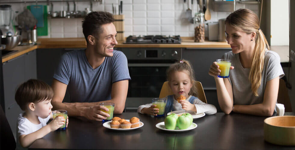 Family sitting at kitchen table with juice and fruit