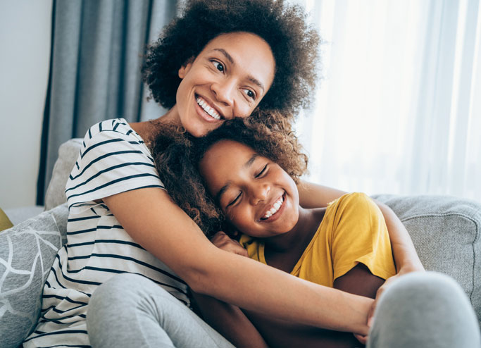 Mother and child hugging on sofa