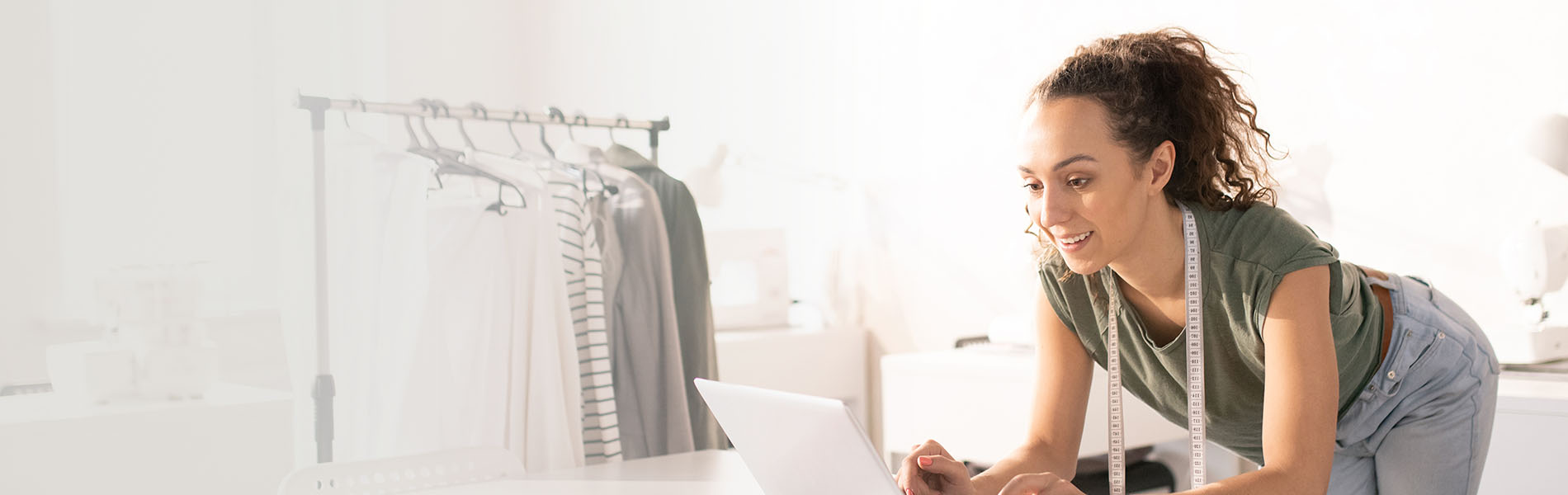 Woman using laptop with tape measure around neck