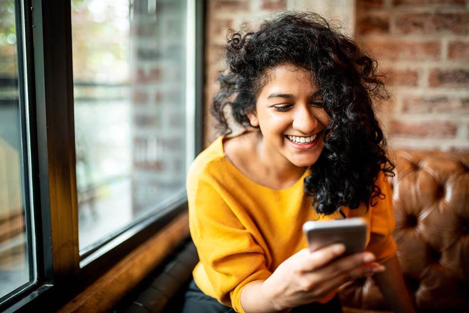 Lady smiling and looking down at the smartphone in her hand