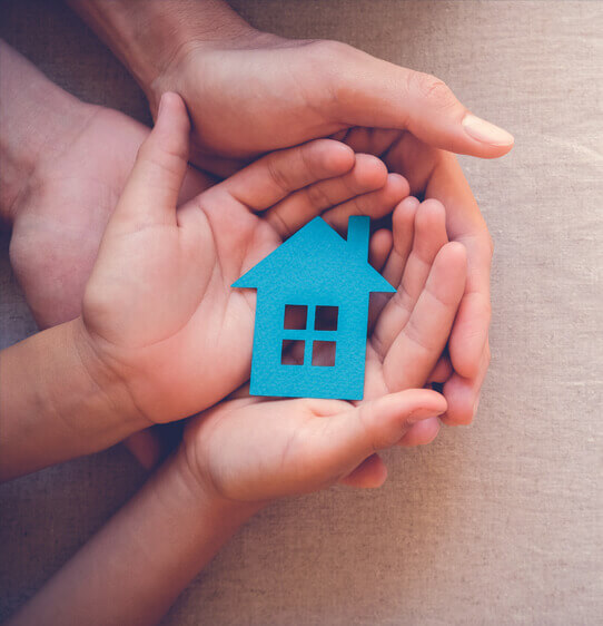 Adult and child hands cupping a blue paper cut out of a house